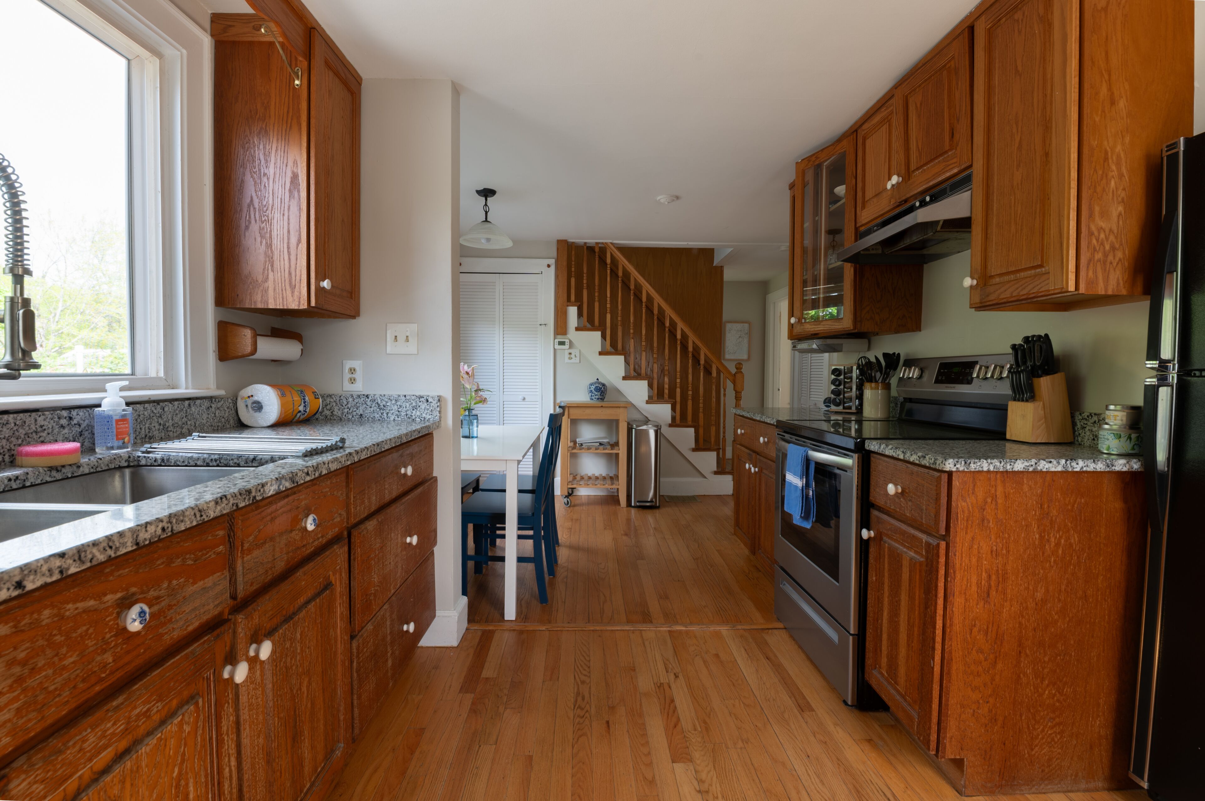 Una cocina con gabinetes de madera, encimeras de granito y un refrigerador de acero inoxidable, además de un horno empotrado.