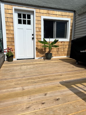 Une terrasse en bois avec une plante en pot et un barbecue.