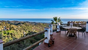 A terrace with a table and chairs overlooking a coastal landscape. - Los Naranjos - Luxury villa with private pool and stunning sea view (Sayalonga)