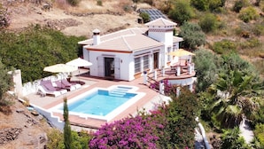 A house with a swimming pool, a patio with lounge chairs, and a solar panel on the roof. - Los Naranjos - Luxury villa with private pool and stunning sea view (Sayalonga)