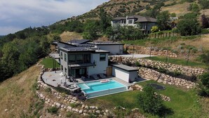 Ein modernes, zweistöckiges Haus mit Swimmingpool und einer Steinmauer.