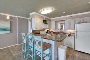 Une cuisine moderne avec des meubles blancs, un îlot central et des tabourets de bar.