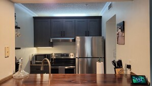 A modern kitchen with dark cabinets, stainless steel appliances, and a wooden countertop. - Sunsets and Sand dunes (Myrtle Beach)