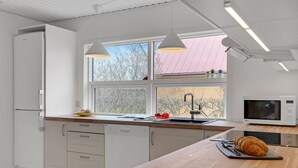 A modern kitchen with white cabinetry, a wooden countertop, a sink, a microwave, and pendant lights. - Cozy home in Nykøbing M with WiFi (Nykøbing M)