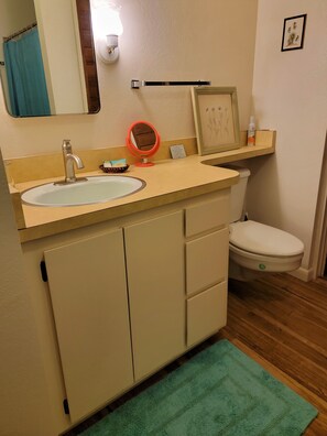 Un bagno con lavandino, specchio, WC e un quadro appeso al muro.