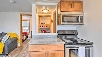 A compact kitchen with wooden cabinets, a built-in microwave, and a stove.