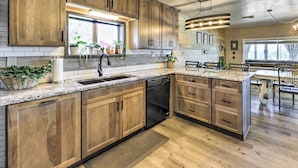 Eine moderne Küche mit Holzschränken, Granit Arbeitsplatten und einem eingebauten Geschirrspüler.