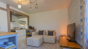 A modern living room with a sofa, a TV, and a wooden table. - La Louvière - JEUGNY - Gîte (JEUGNY)