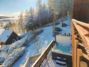 A wooden cabin with a hot tub and a wooden deck.