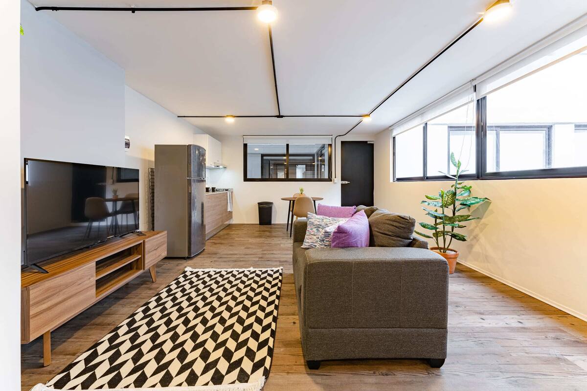 Una sala de estar moderna con sofá, televisor y alfombra estampada.