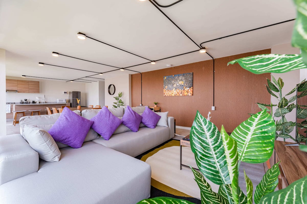 Una sala de estar moderna con un sofá, un comedor y una cocina al fondo.