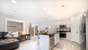 Une cuisine moderne avec des meubles blancs, des appareils en acier inoxydable et un îlot central.