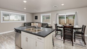 Una cocina moderna con una isla central, lavavajillas integrado y un comedor con mesa y sillas.