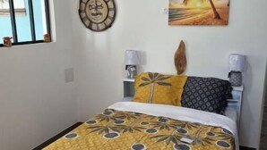 A bedroom with a bed, two bedside lamps, a wall clock, and a painting. - Property in peaceful, central countryside (Ducos)
