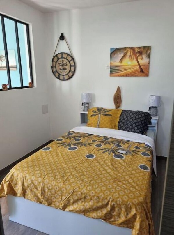 A bedroom with a bed, two bedside lamps, a wall clock, and a painting.