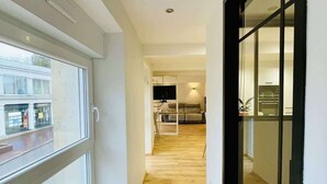 Ein Korridor mit Holzboden, einer Glastür und Blick auf einen Küchenbereich.
