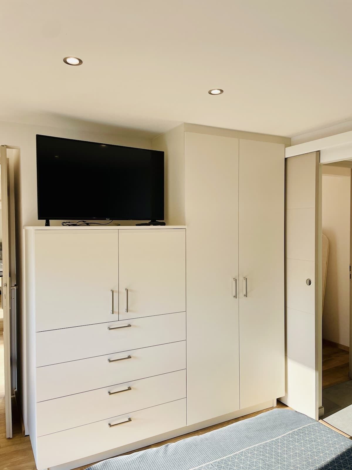 Une chambre à coucher avec un lit, une armoire et un téléviseur.