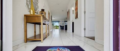 Un pasillo con una consola de madera, un felpudo morado con el logotipo de Storybook Vacation Homes y una puerta blanca al final.