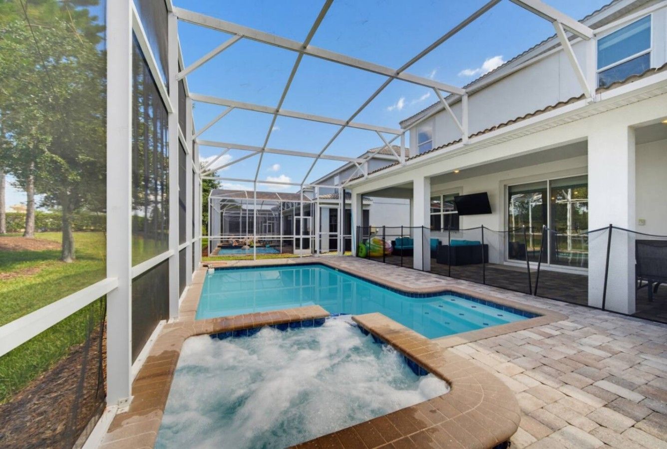 Piscina exterior techada con un jacuzzi, rodeada por un recinto de vidrio y una zona de terraza.