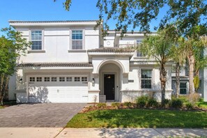 A two-story house with a garage, a front entrance with an arch, and a well-maintained lawn.