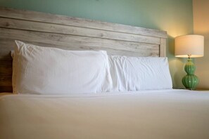 A bed with white linens, a wooden headboard, and a green lamp on the nightstand. - Outstanding 8BR Resort Pool Home Near Disney World (Four Corners)