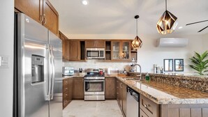 A modern kitchen with stainless steel appliances, wooden cabinets, granite countertops, and pendant lighting. - Best Cabo Bay View, Quite, Ventanas (Cabo San Lucas)