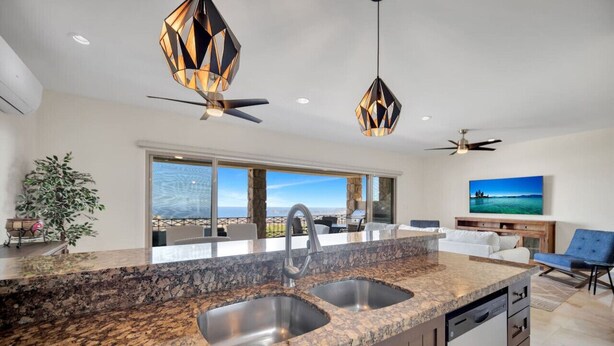 A modern kitchen with granite countertops, double sinks, and a dishwasher. There is a dining area with a view of the ocean. - Best Cabo Bay View, Quite, Ventanas (Cabo San Lucas)