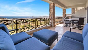A balcony with blue cushioned seating, a grill, and a view of the sea. - Best Cabo Bay View, Quite, Ventanas (Cabo San Lucas)