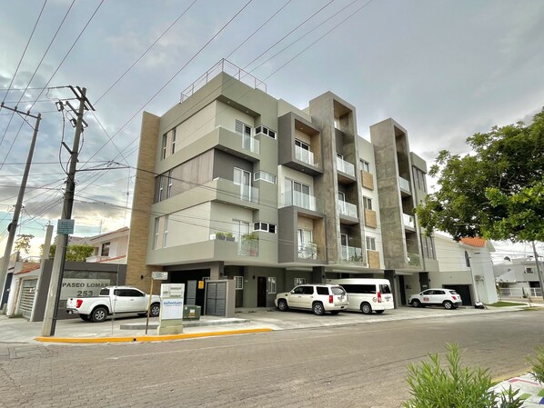 Un immeuble à plusieurs étages, doté d’une architecture moderne, avec des balcons et un toit plat.