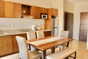 Une cuisine moderne avec des meubles en bois, un four à micro-ondes, un réfrigérateur et un coin repas comprenant une table et des chaises.