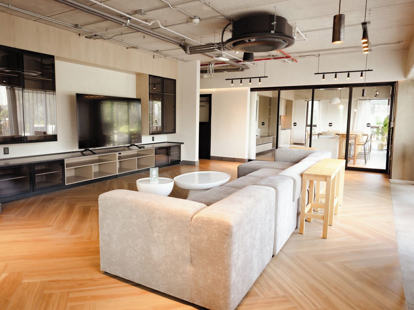 A modern living room with a large sectional sofa, a flat-screen TV, and a dining area with a wooden table and chairs.