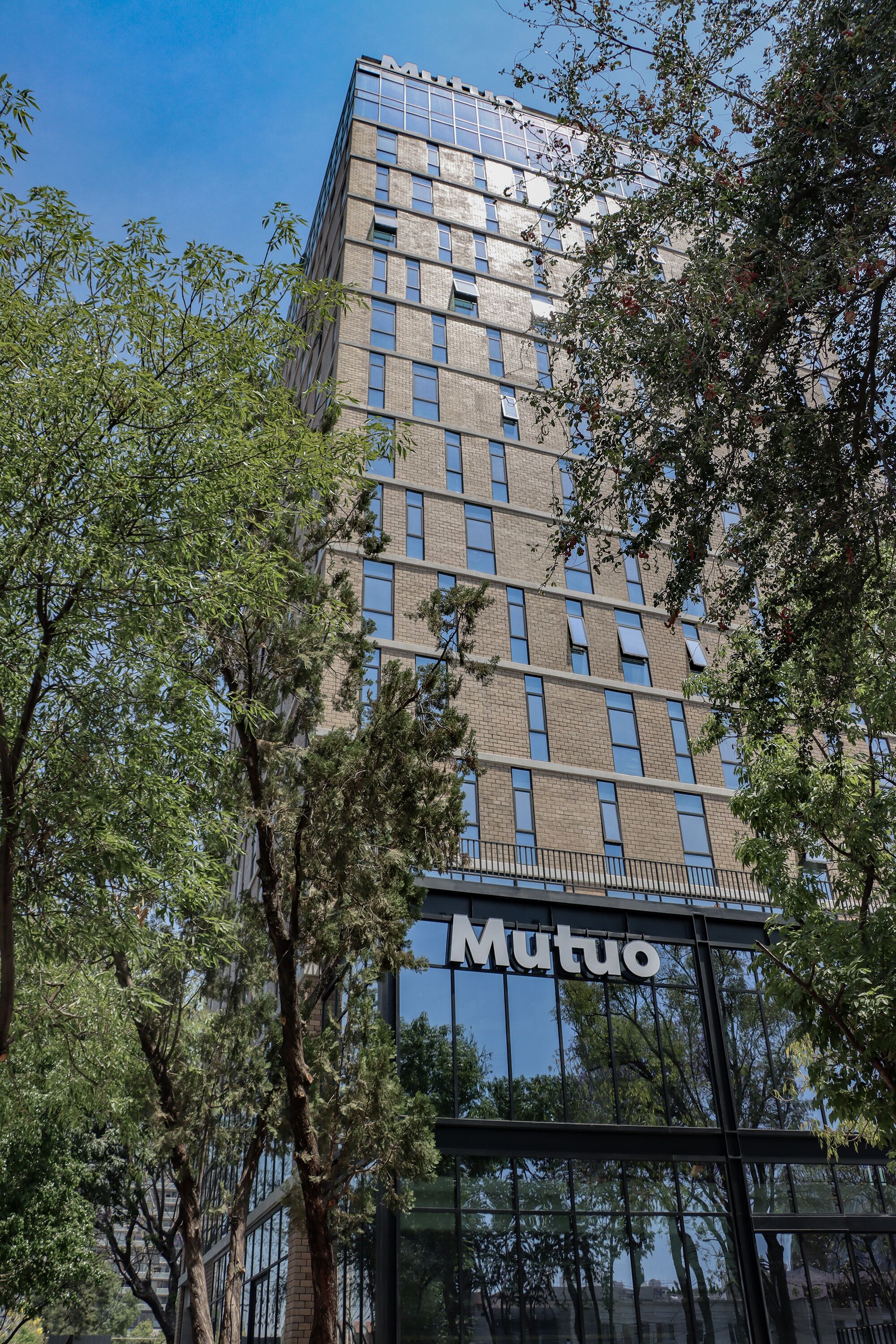 A modern building with a glass facade and the name "Mutuo" on the lower part.