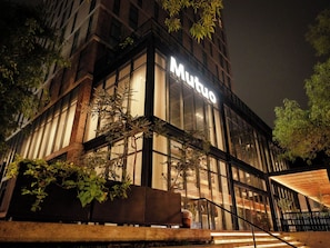 A building with a prominent 'Mundo' sign, large windows, and a staircase leading to the entrance.