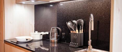A modern kitchen with wooden cabinets, a granite countertop, stainless steel sink, and various kitchen appliances.