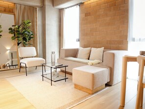 A modern living room with a sofa, two chairs, a coffee table, and a brick wall.