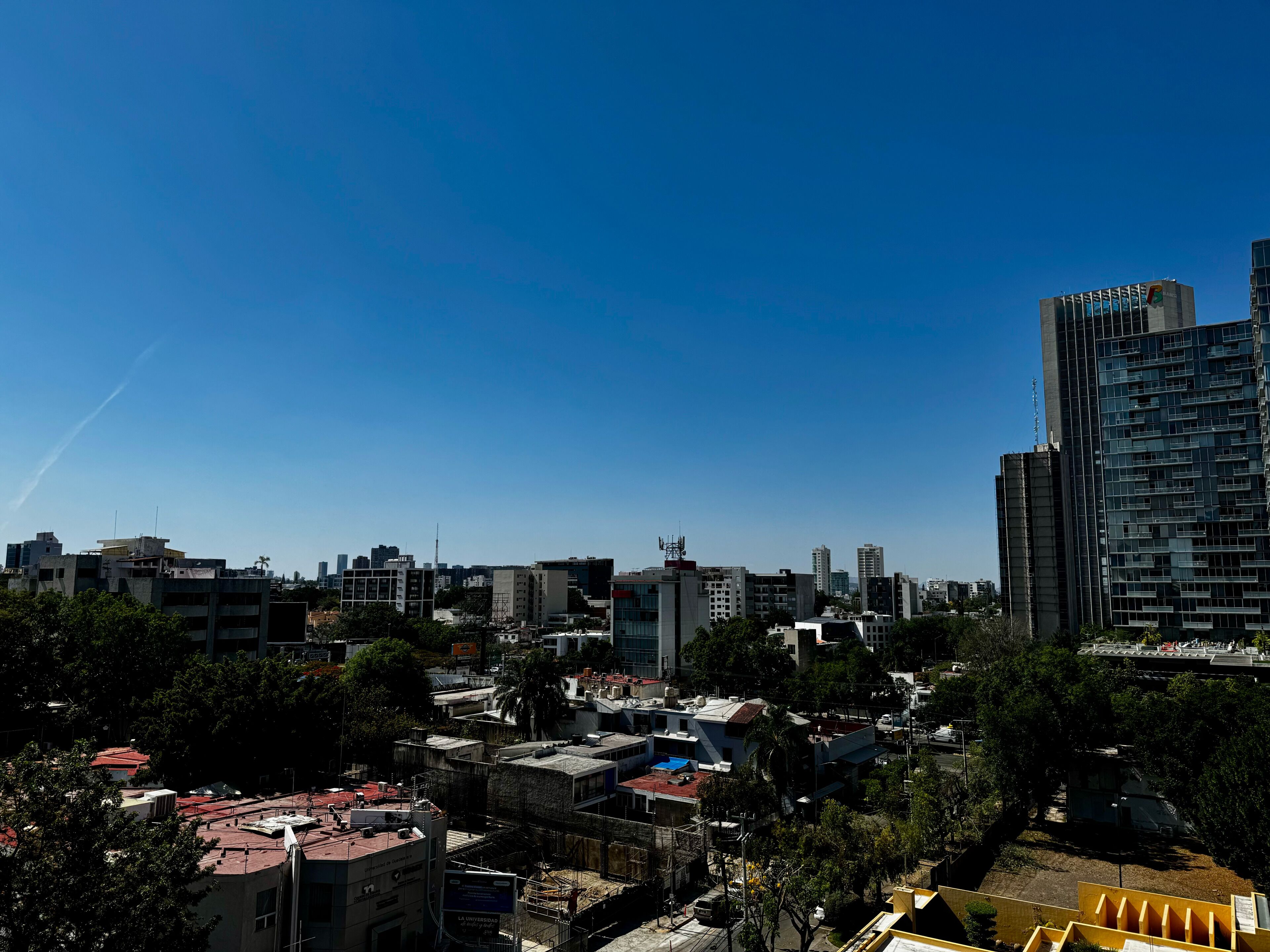 Uma paisagem urbana com diversos edifícios, incluindo um arranha-céu moderno e vários prédios de altura média.