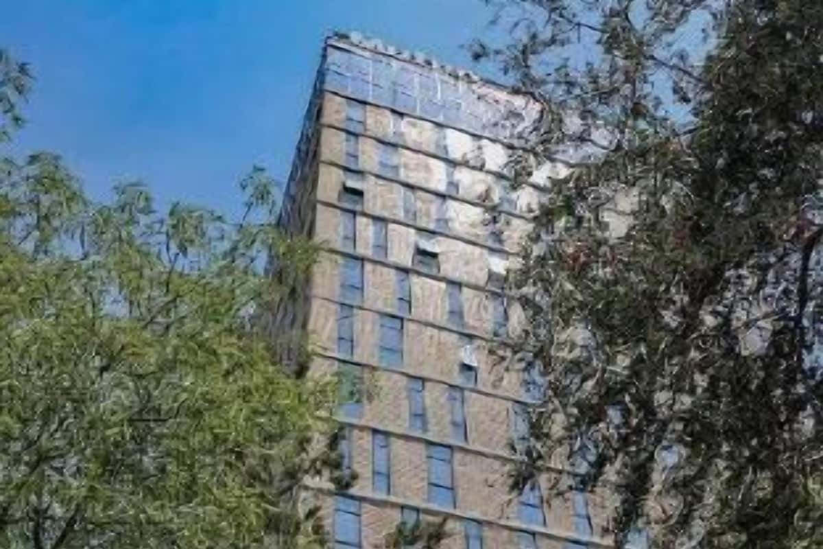 Un edificio alto con un letrero de 'Mutuo', rodeado de árboles.