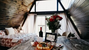 A cozy room with a bed, a table with a cheese board, a bottle of wine, and a welcome sign. - Stunning, Secluded A-Frame w/ Hammock and Tree Top View (New Braunfels)
