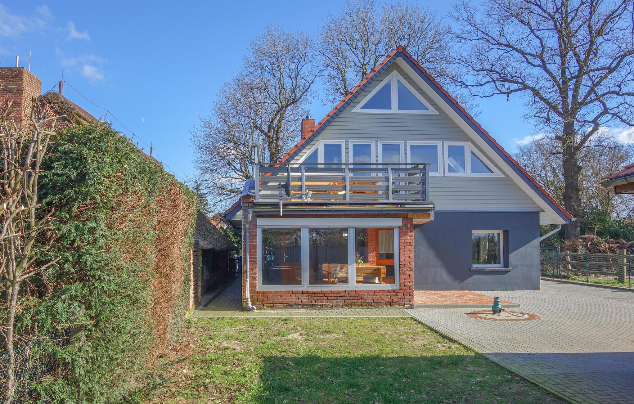 Une maison à deux étages avec un balcon, une façade en briques et de grandes fenêtres.