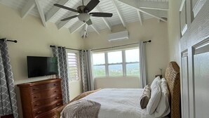 Un dormitorio con cama, cómoda de madera, televisor y ventilador de techo.
