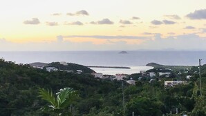 Un paisaje costero con edificios en una ladera, una masa de agua y una isla distante.