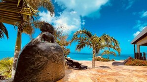 Una escultura de piedra en un entorno tropical, con vista despejada al océano y palmeras.