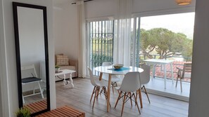 En moderne stue med spiseplads, store vinduer og en balkon med udsigt.