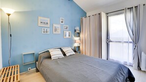 A bedroom with a bed, a bedside table, a lamp, and a window with curtains. - Seignosse-océan Villa Patio 4 Personnes (SEIGNOSSE)
