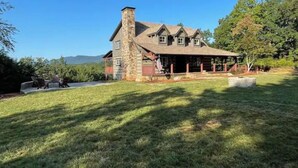 A large stone house with a covered porch and a stone chimney.