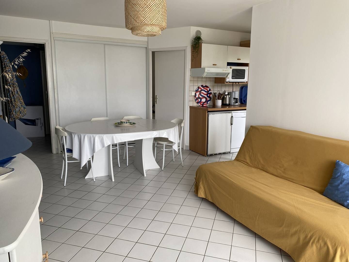 Un espacio habitable compacto con una mesa de comedor, un sofá, una kitchenette y una puerta que da a otra habitación.