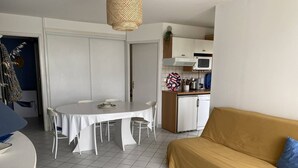 Un ambiente compatto con tavolo da pranzo, divano, angolo cottura e una porta che conduce a un'altra stanza.