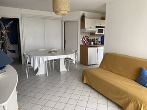 Um espaço de estar compacto com mesa de jantar, sofá, cozinha compacta e porta que dá para outro quarto.