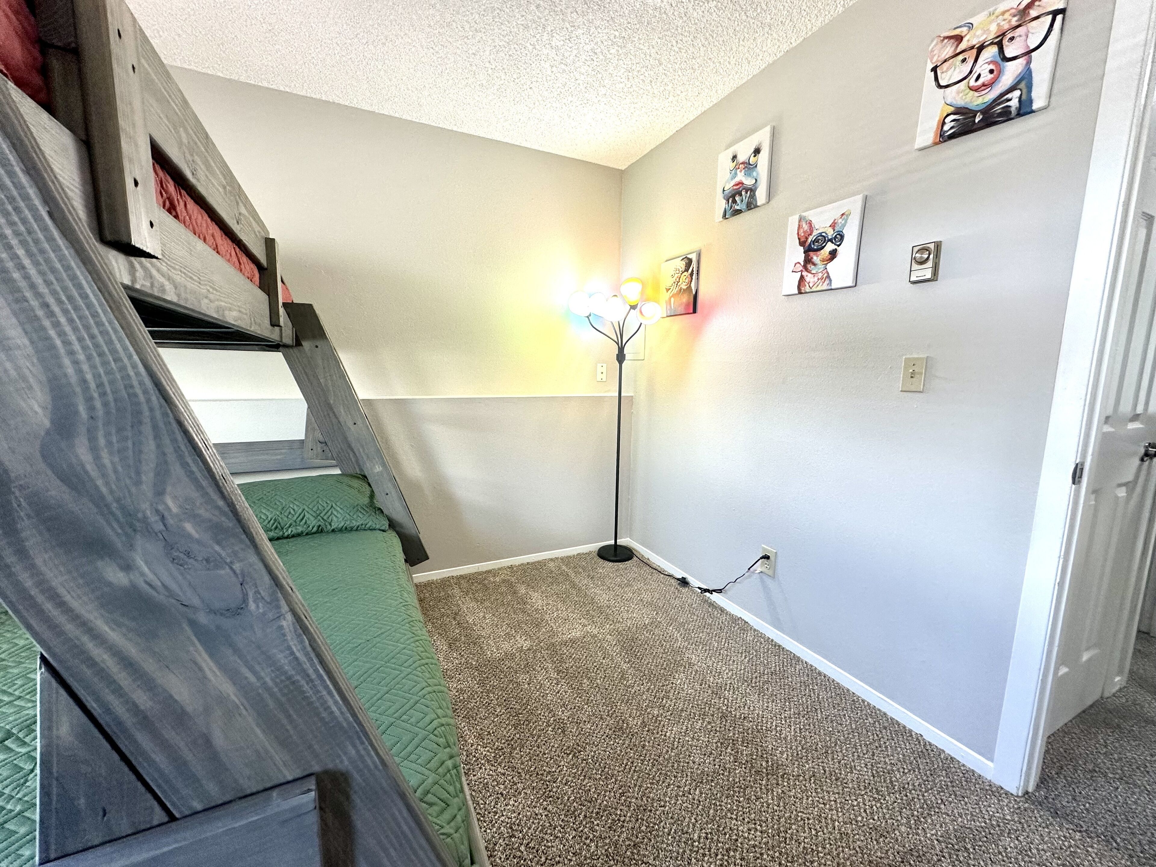 A room with a staircase, a standing lamp, and wall art.
