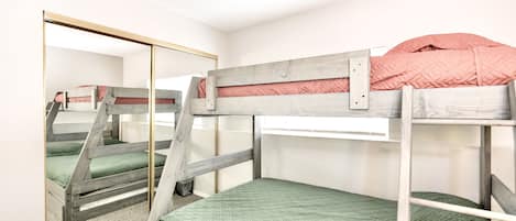Een slaapkamer met een stapelbed, een spiegelkast en een groene gewatteerde matras.